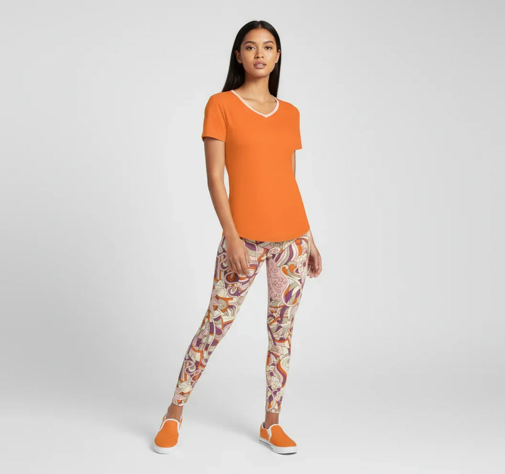 Amai Leggings with psychedelic purple, pink, and orange swirl pattern, paired with orange canvas sneakers, showcasing premium fabric comfort and style. Blissfully Brand