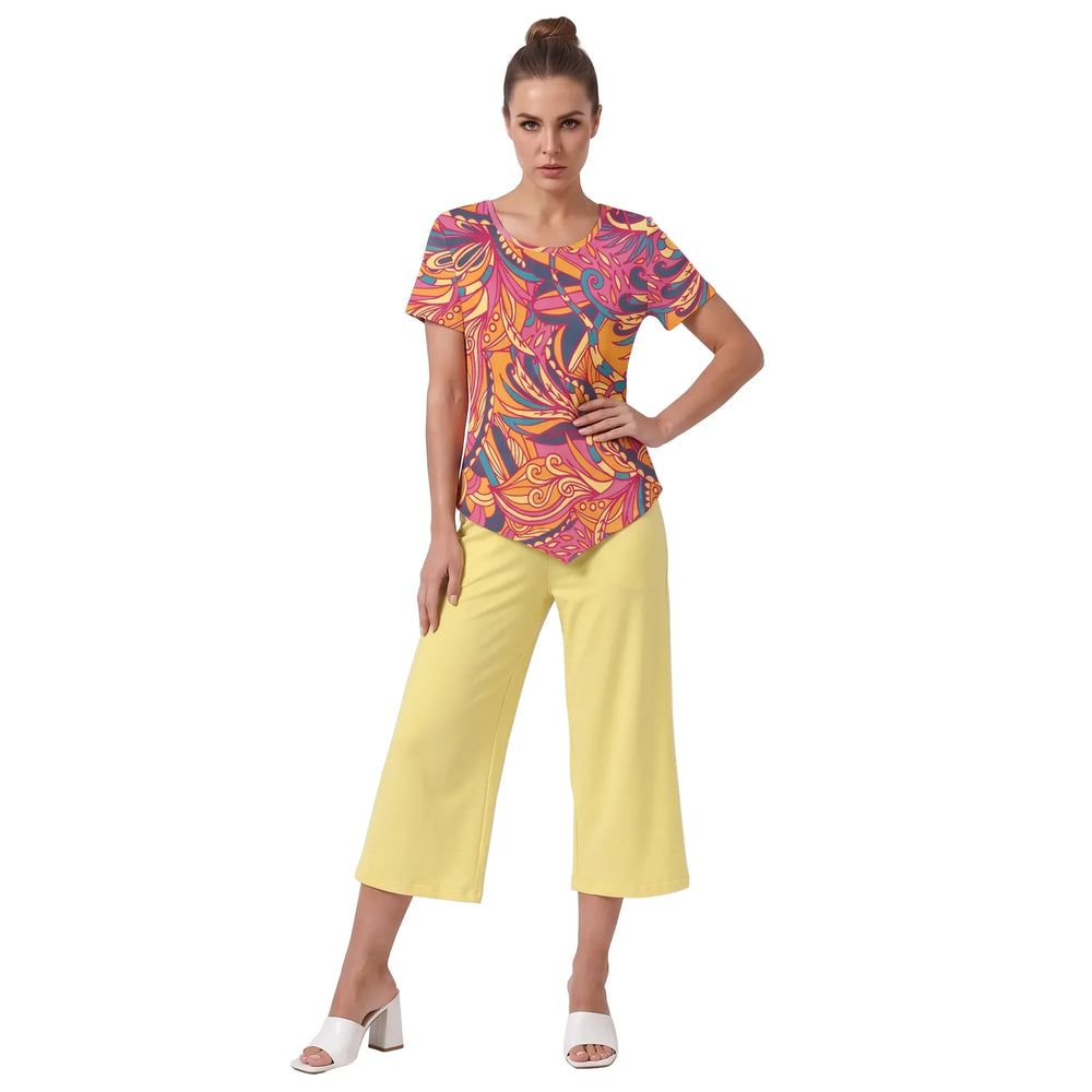 Woman wearing Brisa print handkerchief-hem top with yellow cropped wide-leg pants and white block heels, bold pink orange psychedelic pattern, Blissfully Brand