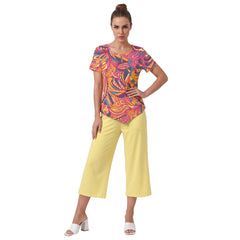 Woman wearing Brisa print handkerchief-hem top with yellow cropped wide-leg pants and white block heels, bold pink orange psychedelic pattern, Blissfully Brand