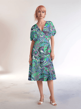 Bold and vibrant Nela dress by Blissfully Brand, featuring a retro chic design with a kaleidoscopic swirl of teal, purple, and green patterns, perfect for making a statement among bold, stylish dressers with a love for vintage-inspired flair.