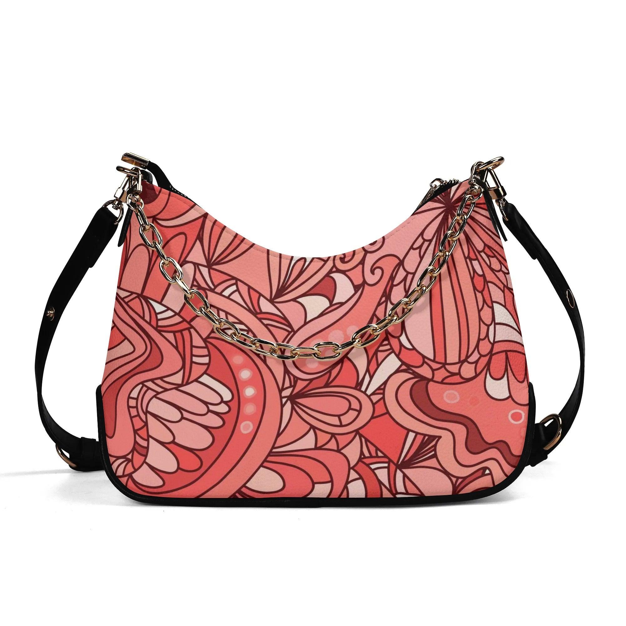 Stylish coral pink designer handbag with intricate floral patterns and elegant gold chain accent 