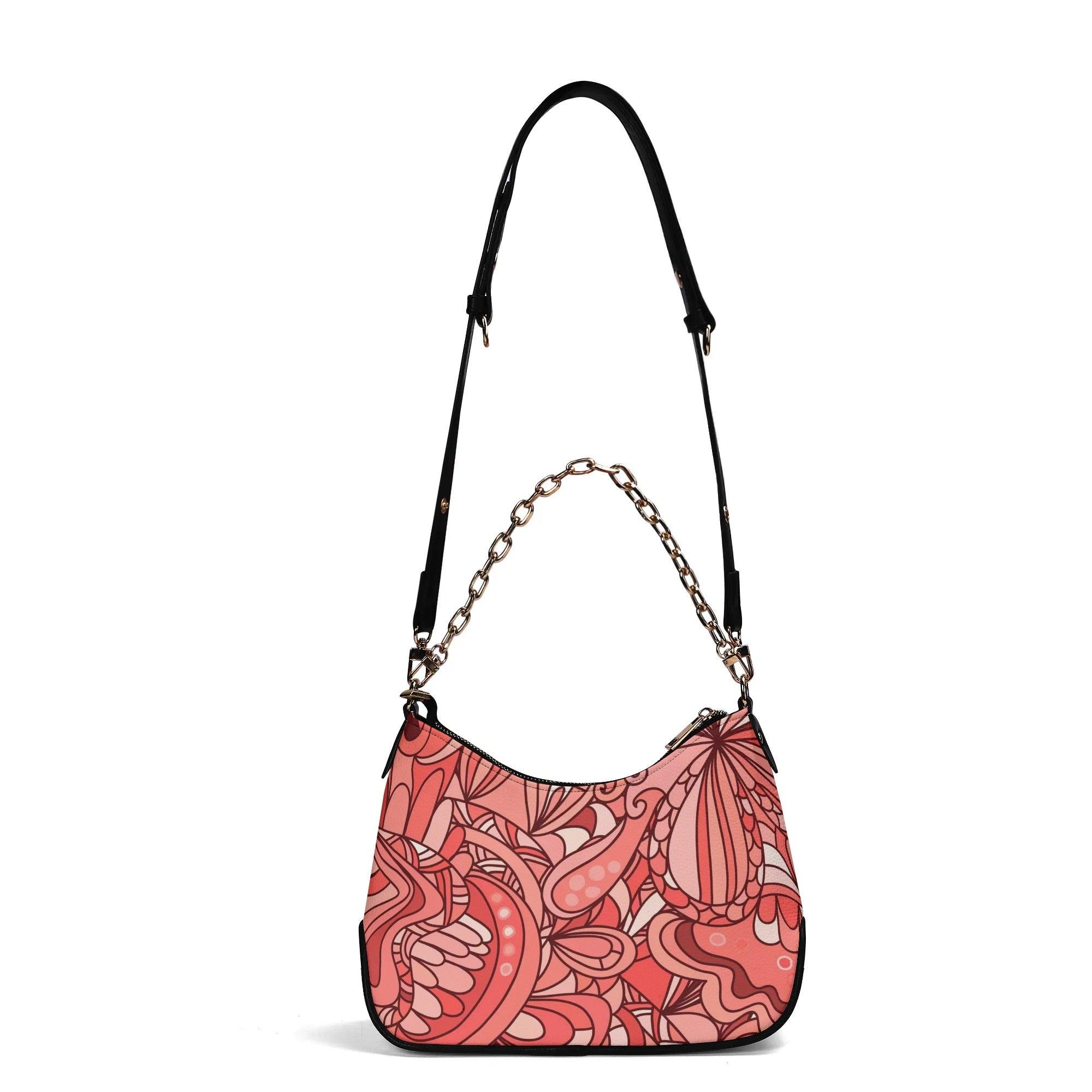 Stylish coral pink designer handbag with intricate floral patterns and elegant gold chain accent 