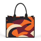 Elevate your style with this striking canvas tote bag featuring a bold, modern abstract design. The vibrant palette of orange, burgundy, black, and cream swirls across the bag in dynamic, curved shapes, creating a visually captivating and artistic statement piece. With its sturdy black handles and sleek rectangular silhouette, this bag perfectly balances form and function. Make a confident, fashion-forward impression while carrying all your essentials in this eye-catching accessory