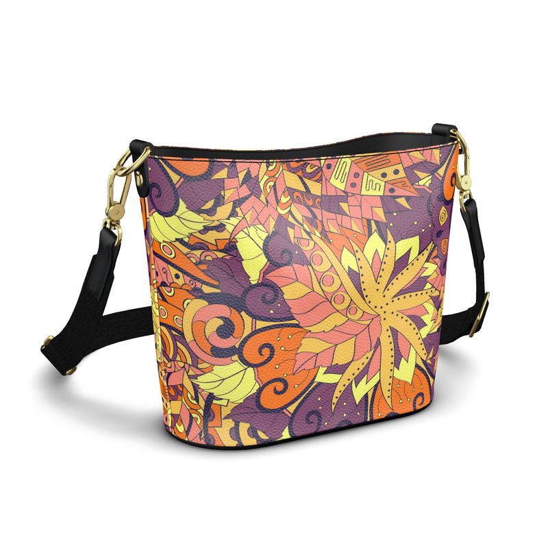 Aki print leather bucket bag in vibrant geometric mandala design featuring orange, yellow, pink and purple hues on textured Nappa leather with black webbing strap and gold hardware - Blissfully Brand