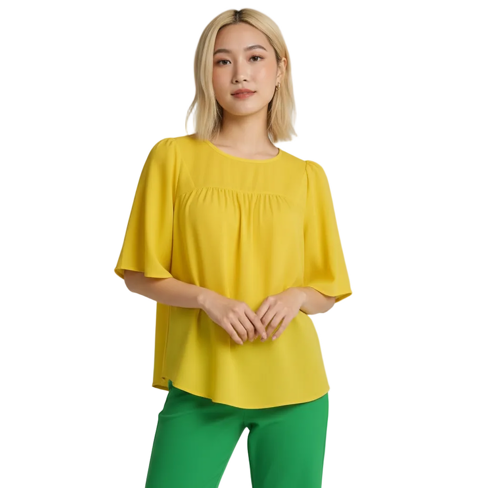 vibrant canary yellow babydoll bell sleeve top with an O-neck, gathered bodice, and flowing bell sleeves, paired with bright green pants. Part of the Core Essentials collection, showcasing a relaxed yet polished style. Blissfully Brand