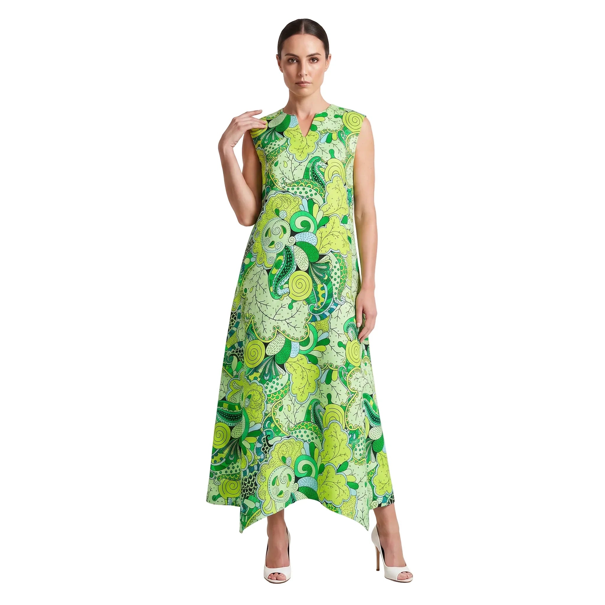 Woman wearing Misa print green botanical paisley handkerchief hem maxi dress with side pockets and white heels - Blissfully Brand