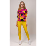 Colorful geometric print raglan tee with pink, purple, yellow, and black abstract pattern, paired with yellow leggings