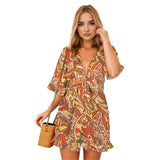 Short-sleeved romper with a V-neckline and front tie knot. The romper features a bold, colorful Miarna print in a retro psychedelic floral theme in autumn colors - Blissfully Brand