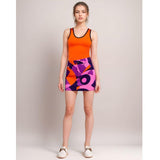 A vibrant and stylish stretch denim mini skirt featuring a bold geometric print in shades of purple, pink, and orange. Tank top ensemble